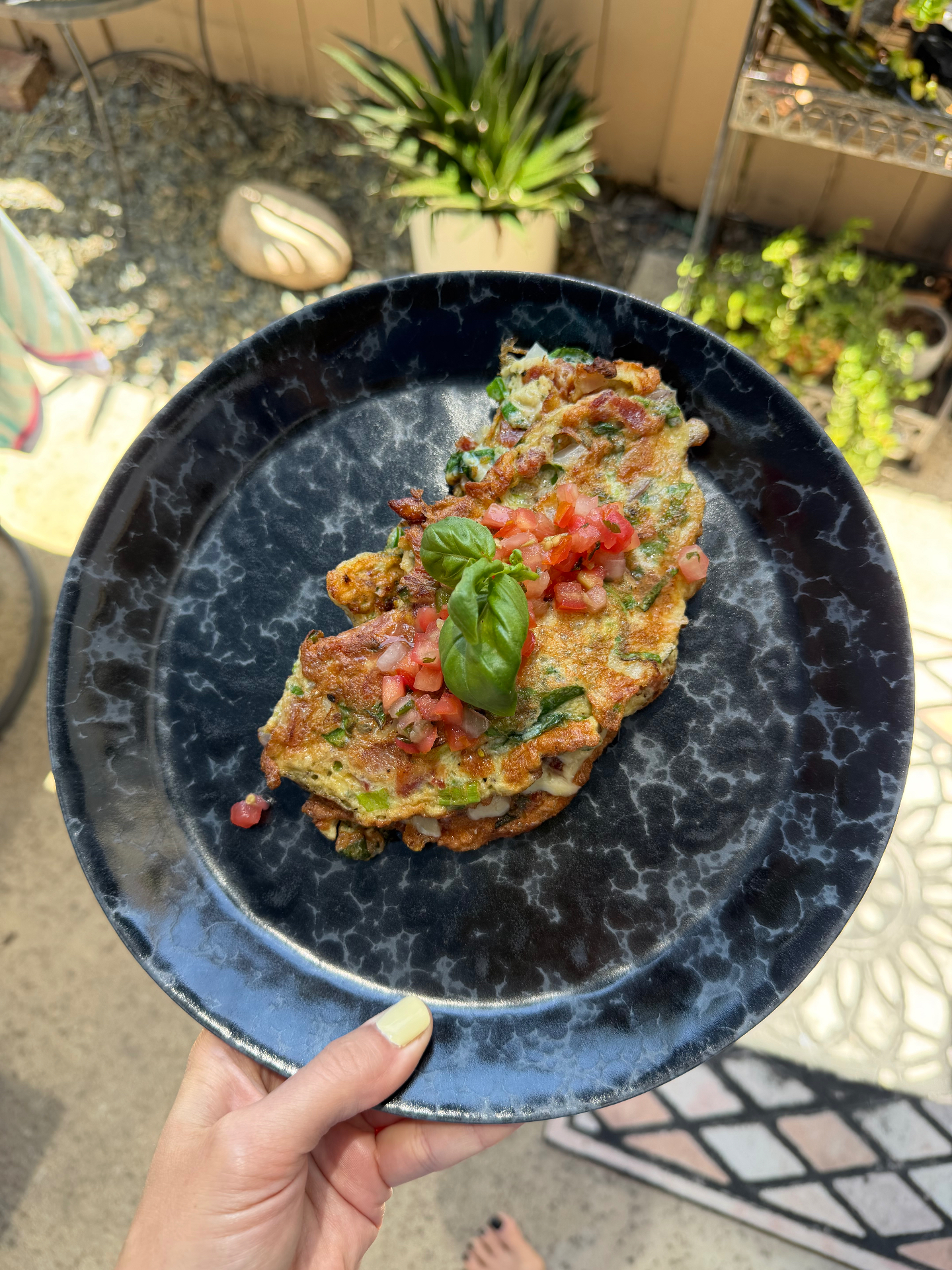A rustic omelette topped with fresh tomato and basil